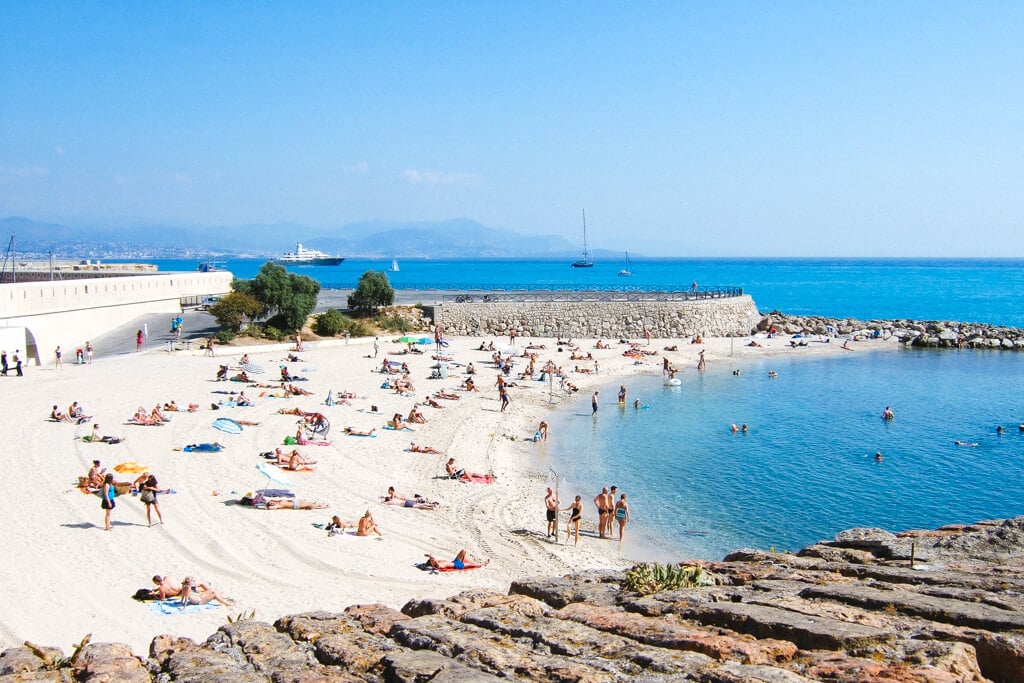 Beach in Antibes with mountains in the background.