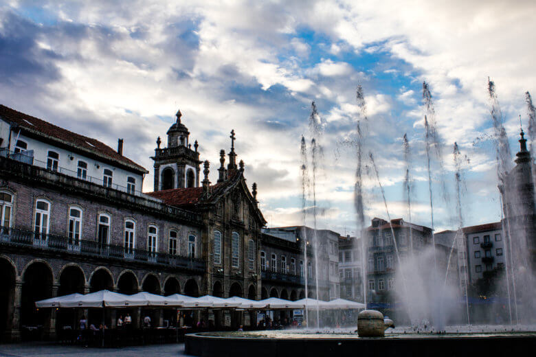 Braga Fountain spraying water with cafes in the background.