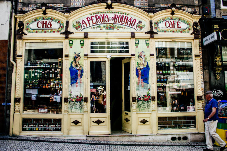 Classic shopfront in Porto with a tiled exterior that depicts women gathering plants. 