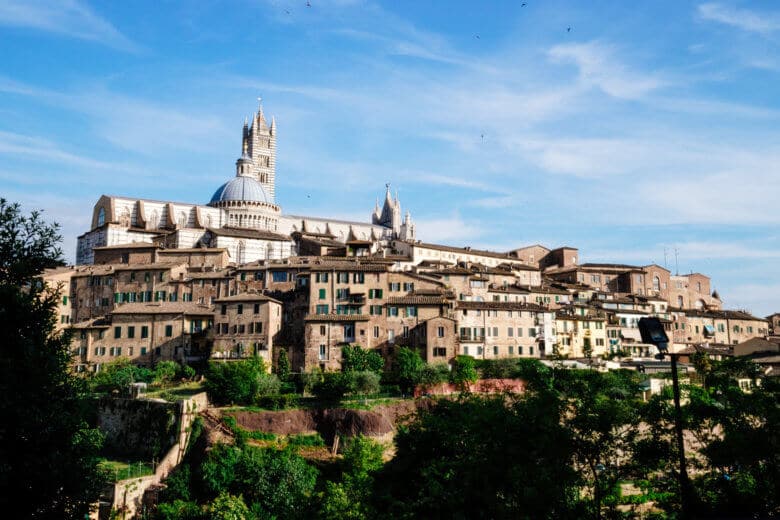 Looking up to the hill in Siena with historic buildings perched on a cliff.