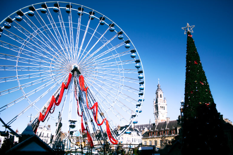 Lille at Christmas with a huge Christmas tree and Ferris wheel on a sunny day with blue sky. 